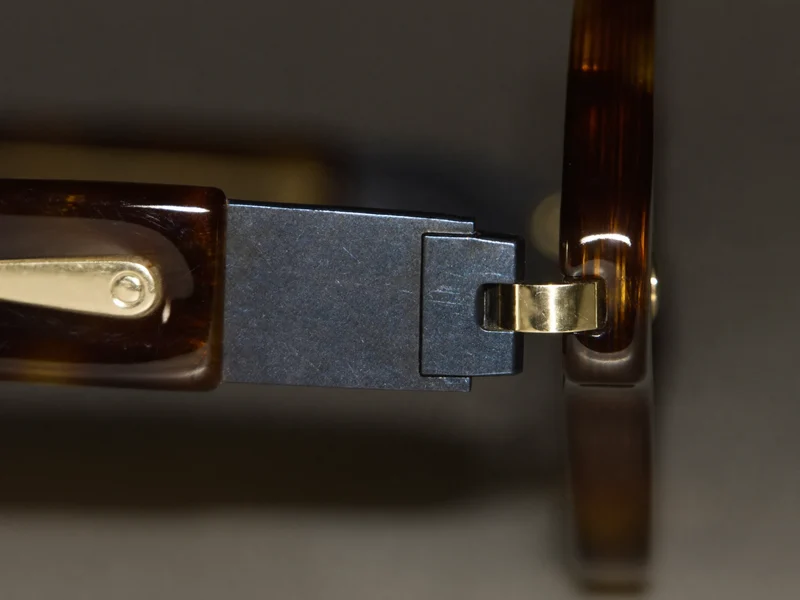Detail leštěného acetátu a jemného kovového kloubu obruby